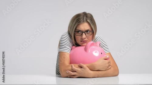 Scared woman trying to protect her piggybank from being stolen