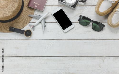 Top view women accessoires to travel concept.White mobile phone,airplane,hat,passport,watch,sunglasses on wood table.
