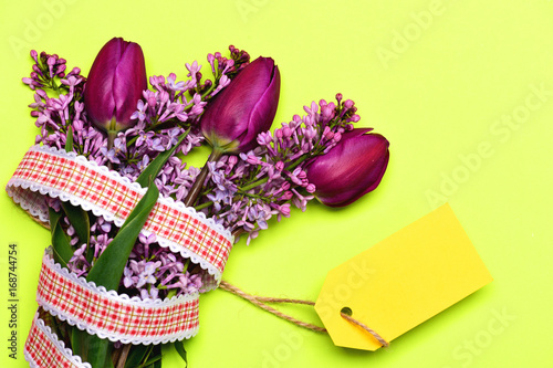 Fototapeta Naklejka Na Ścianę i Meble -  Tulips and lilac flowers in bunch with striking yellow label