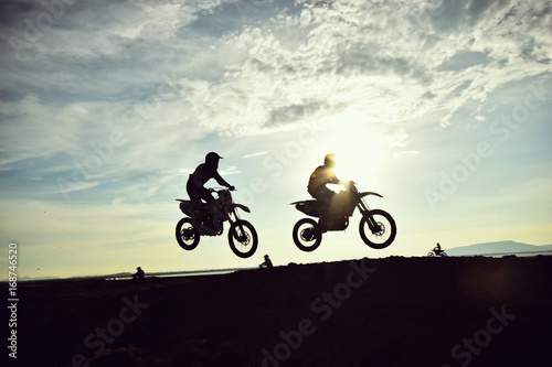The silhouette of a motorcycle motocross jump from the hill at sunset.