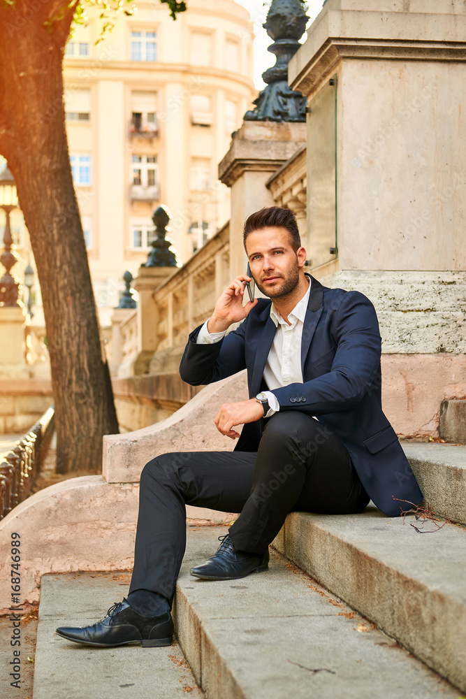 Young businessman siting on the stairs and talking on the phone Young businessman siting on the stairs and talking on the phone