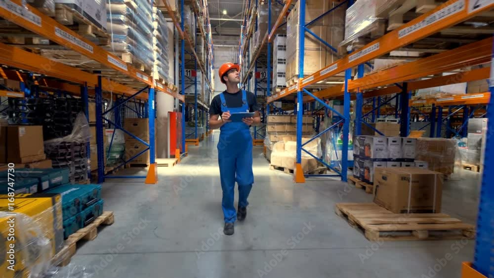 A worker in a uniform walks along a warehouse corridor. A worker in a uniform walks along a warehouse corridor.