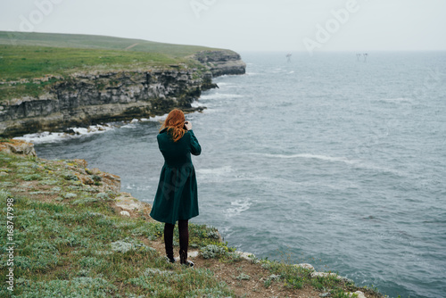 beautiful young woman on the precipice of a mountain near the sea