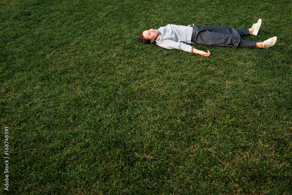 Beautiful young european woman lays down on grass and rests Beautiful young european woman lays down on grass and rests