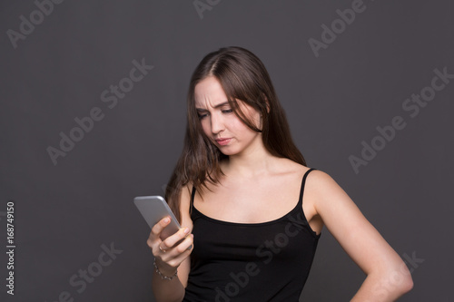 Obraz na plátně Unhappy young woman using smartphone portrait