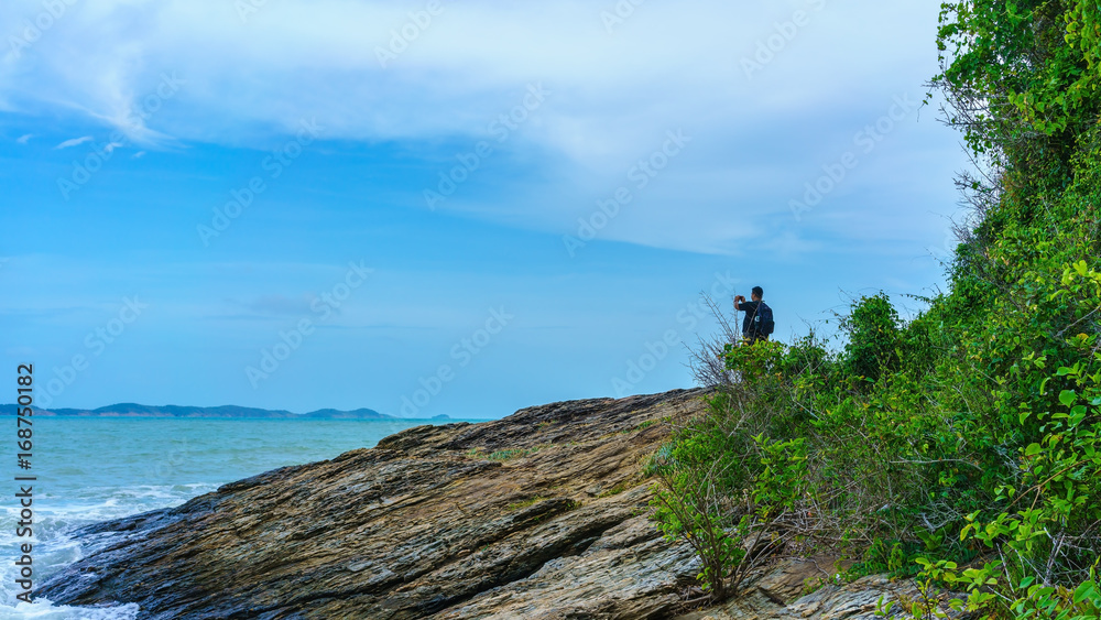 Fototapeta premium Male tourist taking beautiful pictures along the coast at Khao Laem Ya National Park , Rayong ,Thailand
