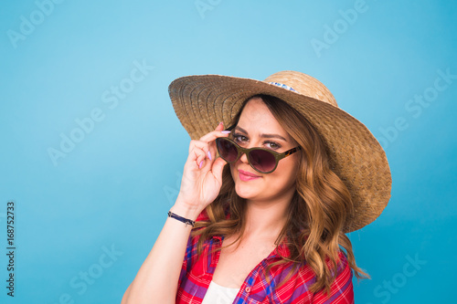 Holidays, summer, fashion and people concept - Girl in fashionable clothes straw hat. Portrait of charming woman on blue background with empty copy space