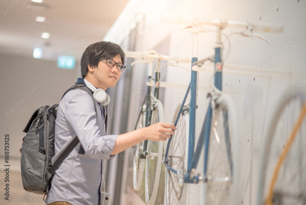 Young Asian man looking vintage bicycle at bike shop in department store, urban lifestyle concept