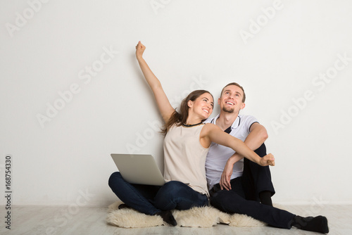 Cheerful couple using laptop at home, copy space