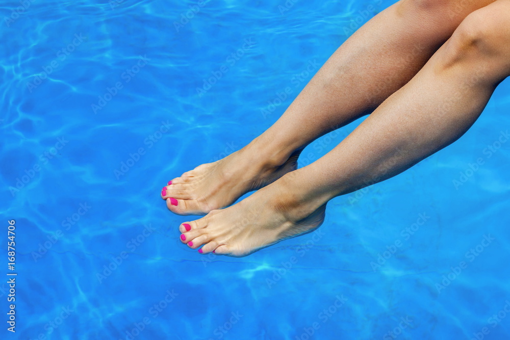 Woman keeping her legs in the swimming pool