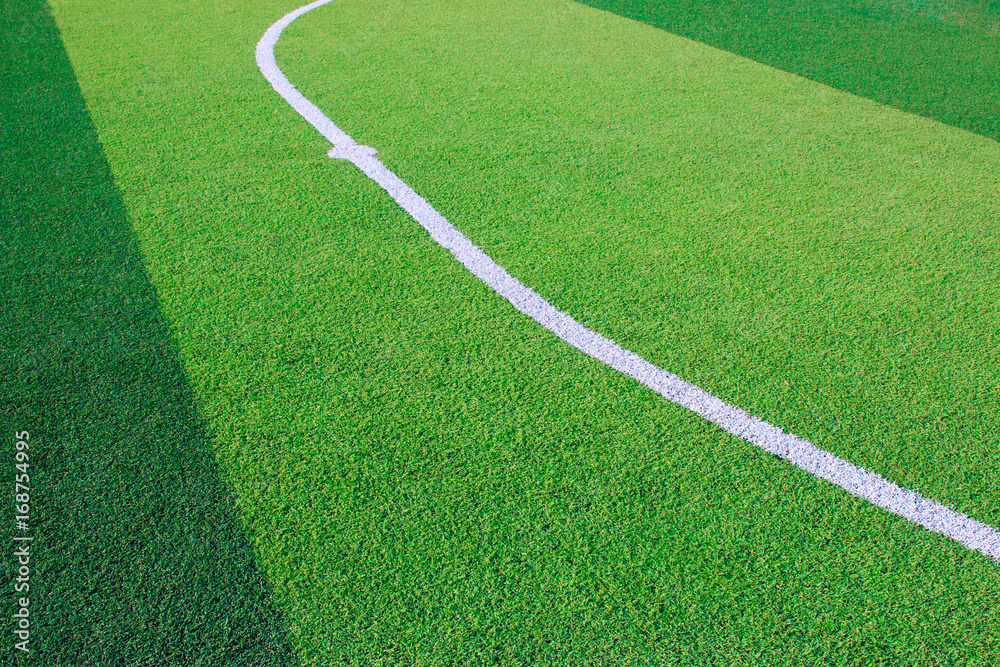 Photo of a green synthetic grass sports field with white line shot from above.