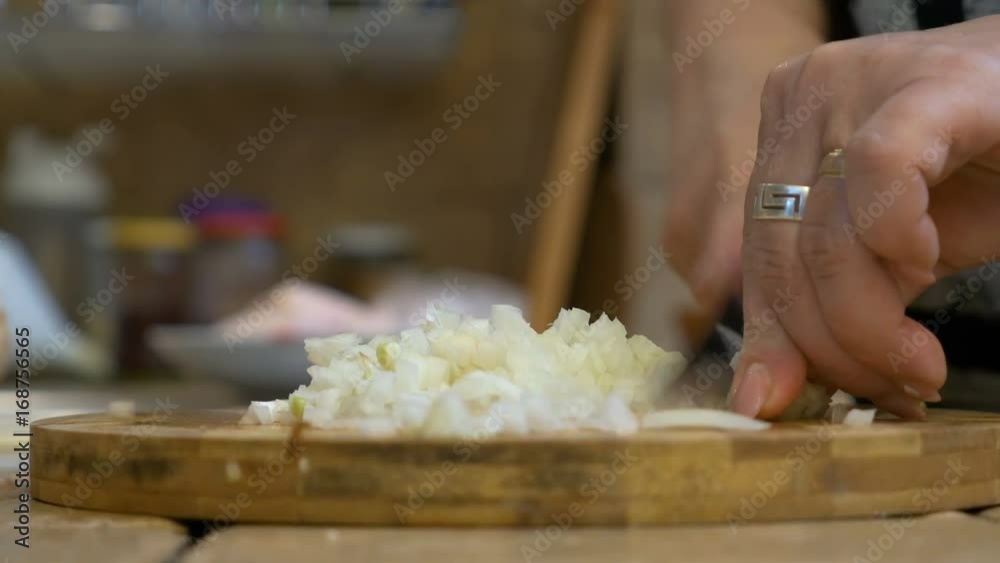 Closeup of middle aged woman hand chopping onions on cutting board Closeup of middle aged woman hand chopping onions on cutting board