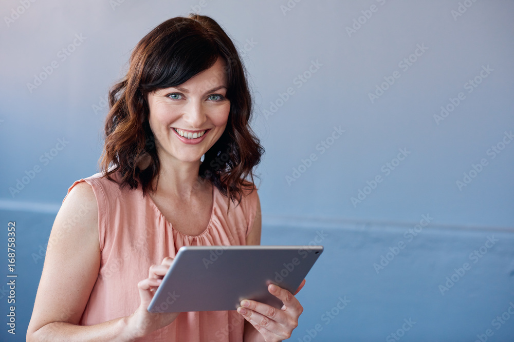 Smiling young businesswoman using a digital tablet in an office Smiling young businesswoman using a digital tablet in an office