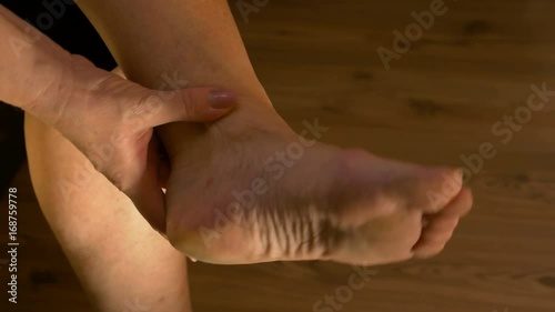 Closeup of woman massaging ankle and stretching foot suffering from pain