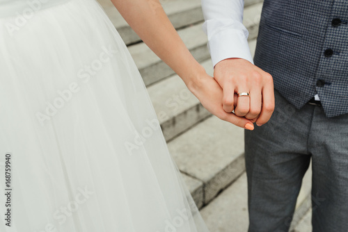 Bride and holding hands at wedding day. Close-up. Wedding ring.