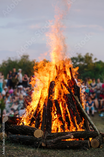 Unrecognizable people watch as huge bonfire burns