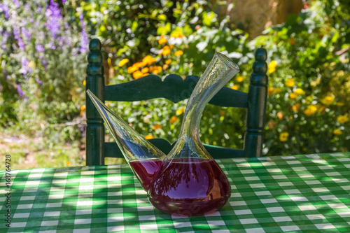 Recipiente para beber Vino tipico de España ( Porron ) con sangria encima de una  mesa a la sombra de verano en el jardin o patio de la casa, con una silla photo