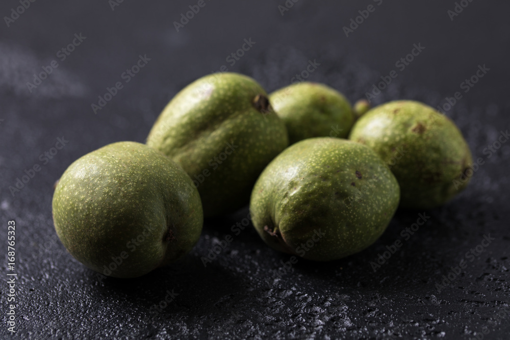 Fresh green walnuts in the skin just from the tree. Walnuts on a black background. Macro. Fresh green walnuts in the skin just from the tree. Walnuts on a black background. Macro.