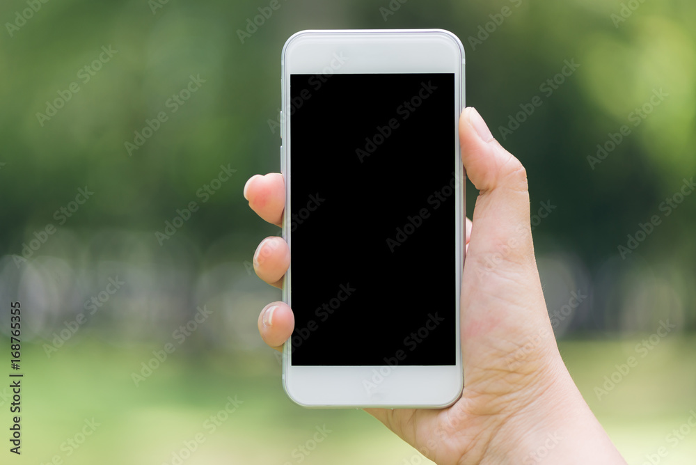 Close-up hand showing on phone mobile blank black screen outdoor lifestyle concept on blurry nature background - can be used mock up image. Vintage effect style pictures. Close-up hand showing on phone mobile blank black screen outdoor lifestyle concept on blurry nature background - can be used mock up image. Vintage effect style pictures.