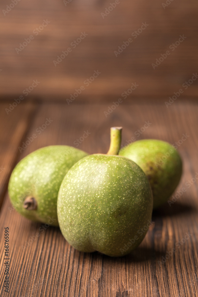 Fresh harvest of walnuts on a wooden background. Green and brown nuts. Shell and peel of walnuts.