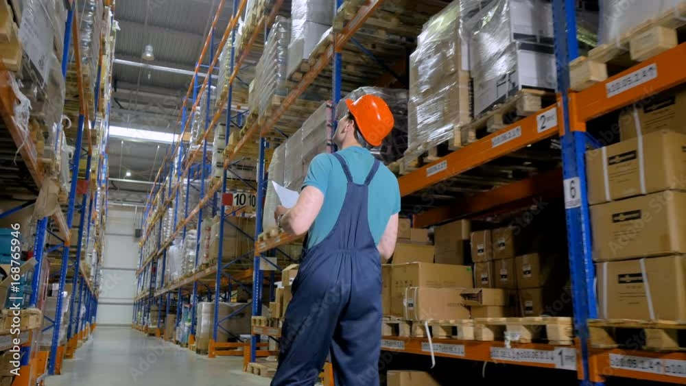 A back view on a walking warehouse inventory officer. A back view on a walking warehouse inventory officer.
