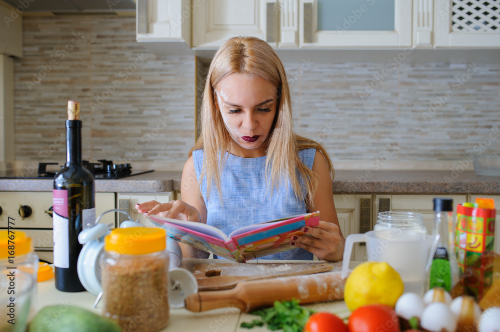 happy housewife reading cooking book in her kitchen happy housewife reading cooking book in her kitchen