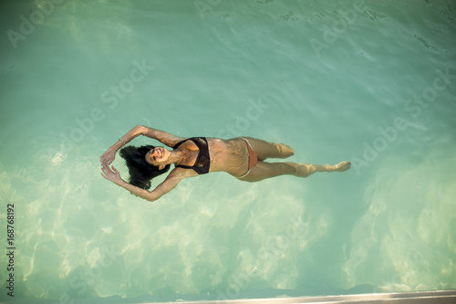 Woman in bikini floating on water in the pool