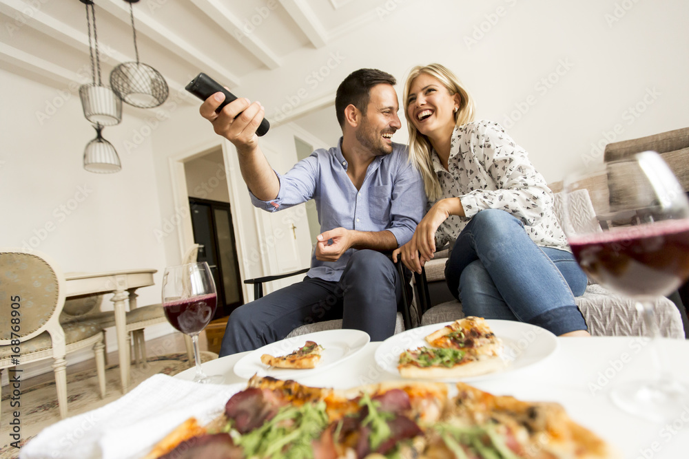 Young couple enjoying eating pizza and watching tv