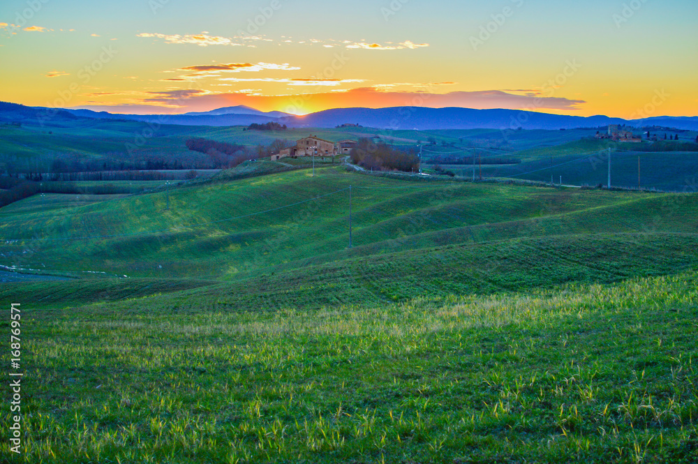 Sunset over the green hills in the Tuscan countryside in the province of Siena Italy.