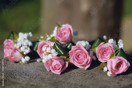 Flower arrangement for wedding centerpiece featuring small pink roses and baby s-breath  positioned on a tree stump  with shallow depth of field