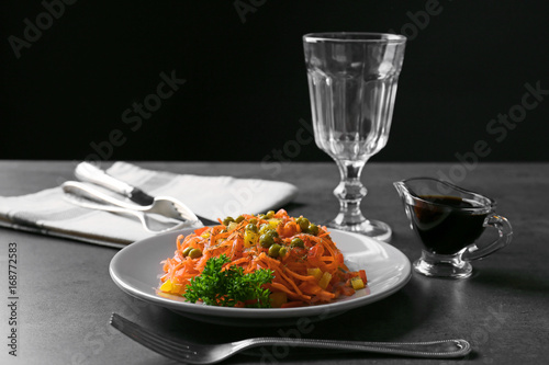 Delicious spicy carrot spaghetti with peas, pepper and parsley on table
