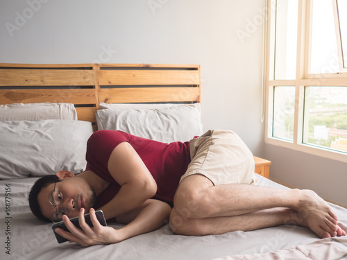 Lonely man playing his phone in his bedroom. photo