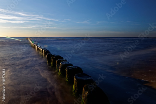Poland, Baltic. Sunset over the sea. Breakwater on the smooth surface of the sea.