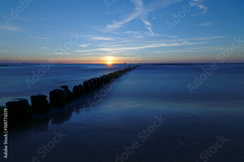 Poland, Baltic. Sunset over the sea. Breakwater on the smooth surface of the sea.