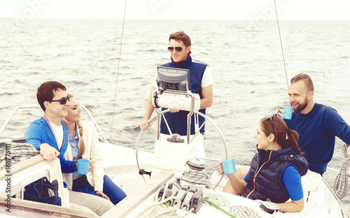 Group of friends traveling on a yacht, enjoying a good summer day and drinking a tea. Vacation, holiday and summertime concept. © Acronym