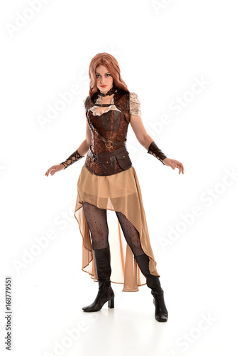full length portrait of a red haired lady wearing steampunk inspired outfit  standing pose against a white background.