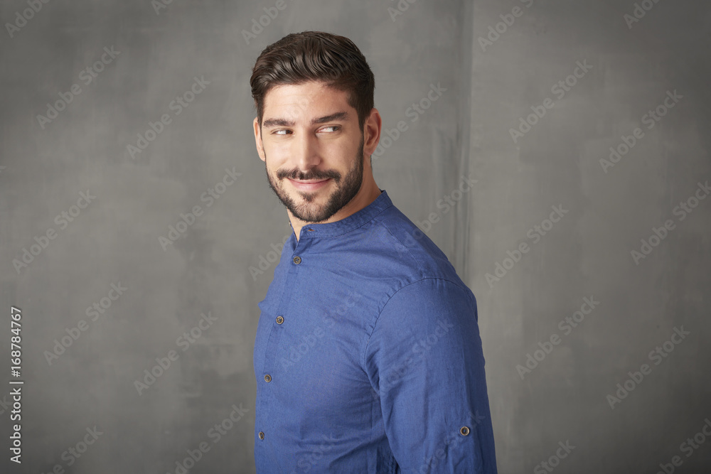 Confident young businessman portrait. Cropped shot a handsome young man standing at grey wall in studio.