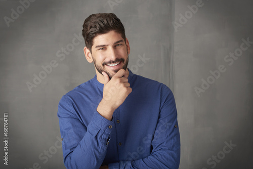 Confident young businessman portrait. Cropped shot a handsome young man standing at grey wall in studio.