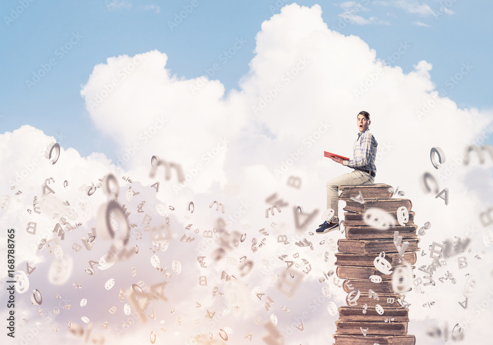Man student on stack reading book and symbols flying around