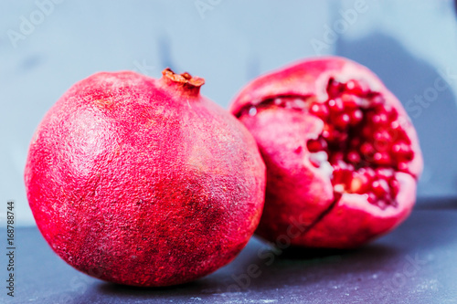 whole and cut pomegranate on dark vintage background with copy space