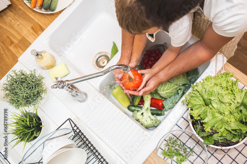 Father with son washes vegetables before eating photo