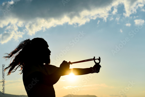 Foto silhouette of the man who throws slingshot