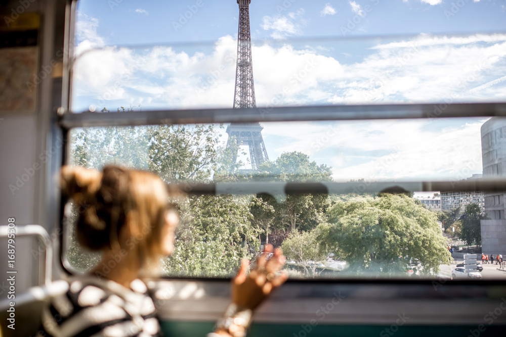Obraz premium Młoda kobieta, patrząc na wieżę Eiffla przez okno pociągu w Paryżu. Obraz skupiony na tle