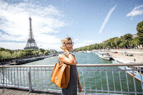Elegant french business woman walking the bridge with Eiffel tower on the background during the sunny weather in Paris