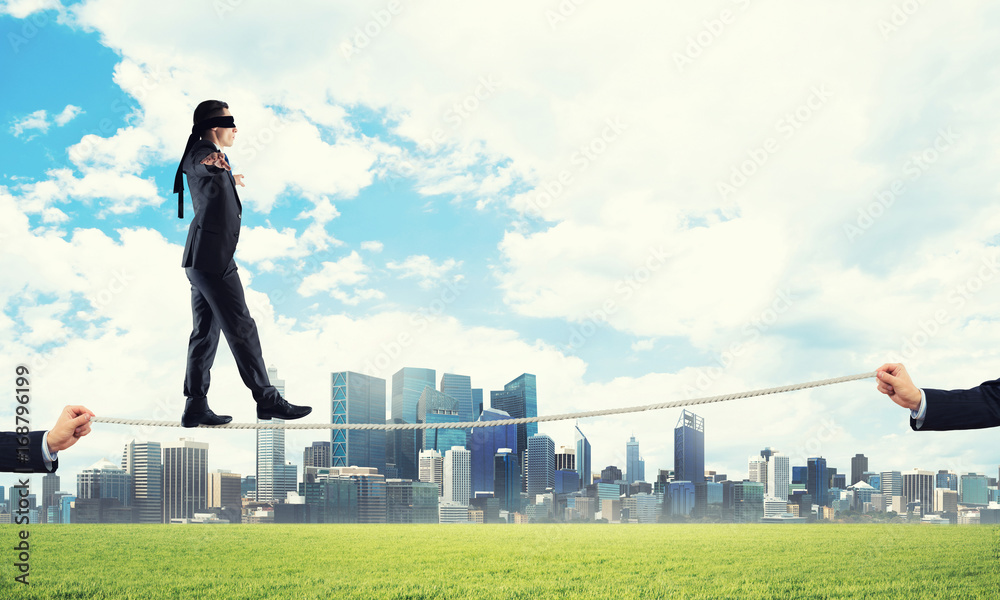 Business concept of risk support and assistance with man balancing on rope Business concept of risk support and assistance with man balancing on rope