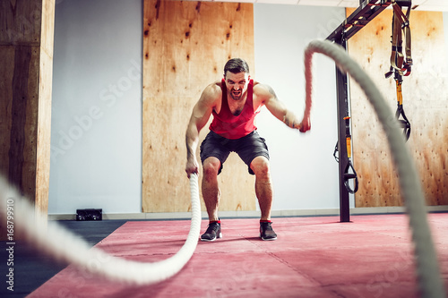 Men with battle rope in functional training fitness gym photo