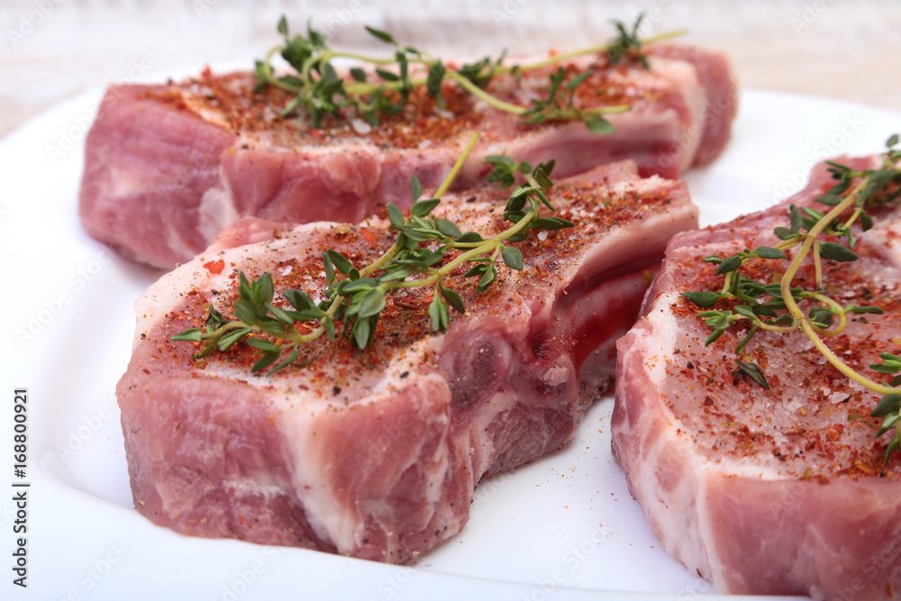 Raw pork chops, spices and rosemary on cutting board. Ready for cooking. Raw pork chops, spices and rosemary on cutting board. Ready for cooking.