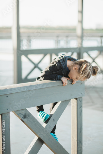 5year old girl climbing the wooden fence on a boardwalk photo