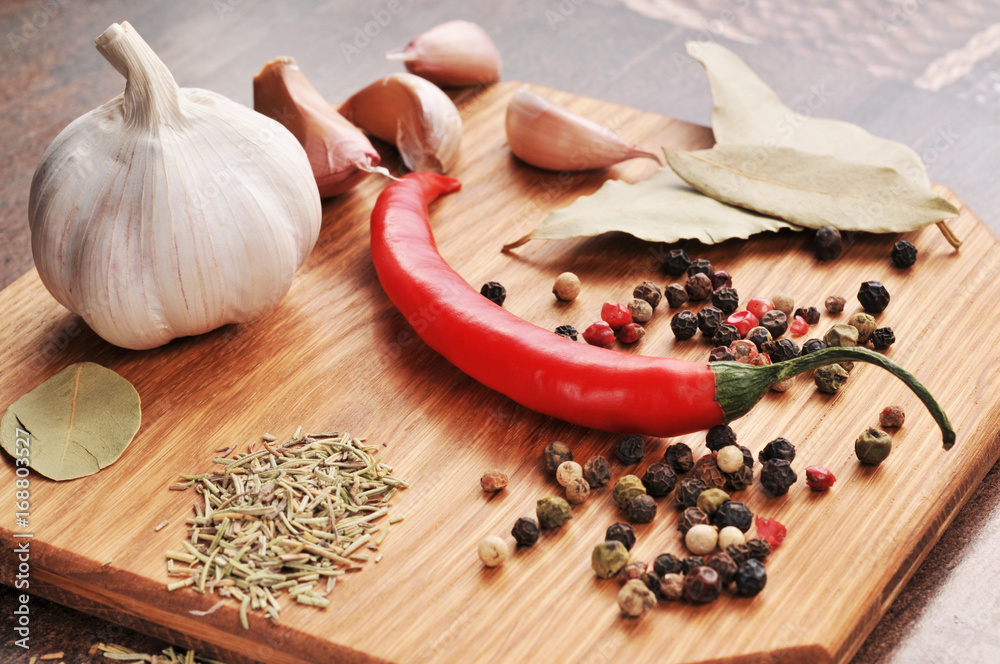 Hot pepper with peppercorns, whole garlic and cloves, bay leaves and dried spices on a board Hot pepper with peppercorns, whole garlic and cloves, bay leaves and dried spices on a board