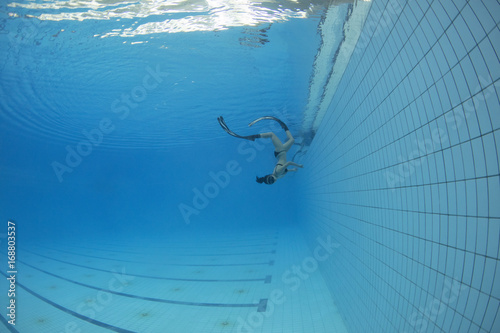 Female freediver swimming underwater in swimming pool